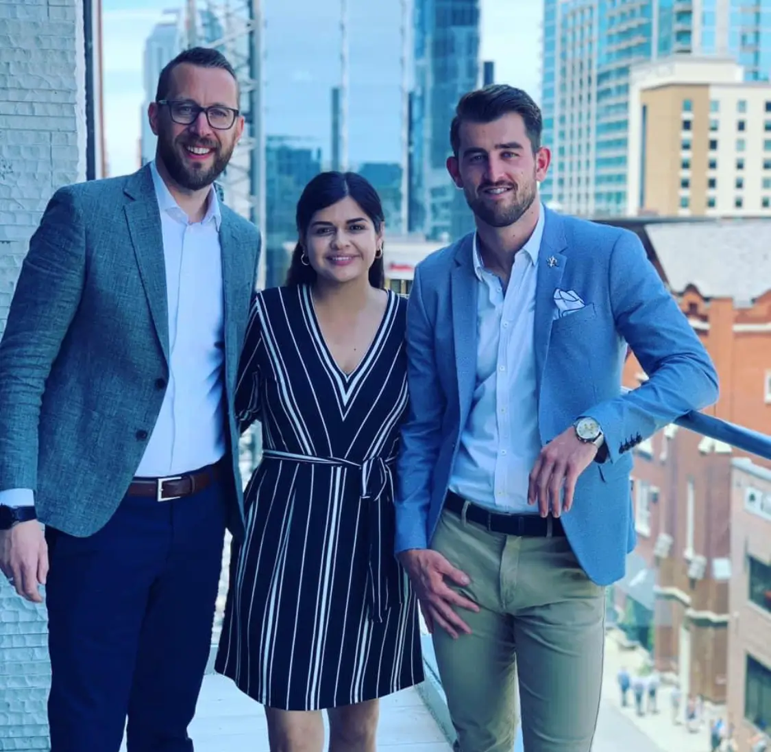 Three people smiling on a balcony.